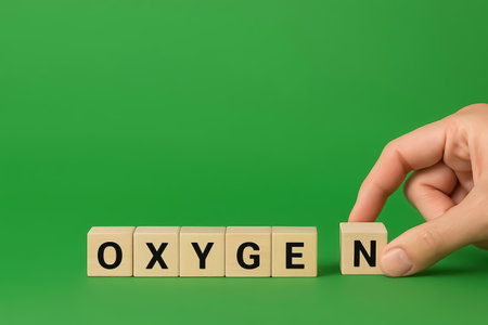 Wooden cubes spelling the word OXIGEN, a hand completes the wordの素材