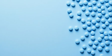 A scattered arrangement of blue pills on a soft blue surface, creating a calming and minimalist aesthetic. Ideal for healthrelated topicsの素材