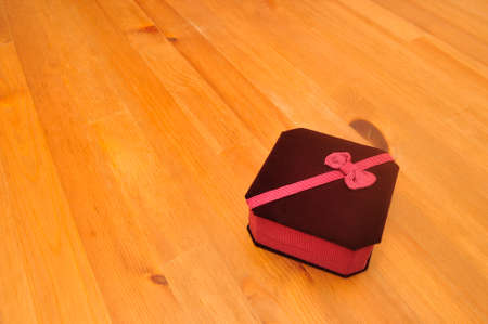 Closed ribbon velvet jewelry box on woodの写真素材