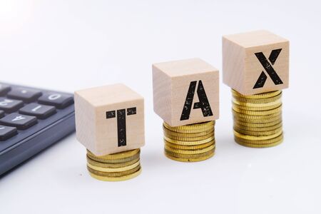 Tax concept with wooden block on stacked coinの写真素材