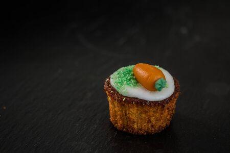 Small round carrot cake on black background