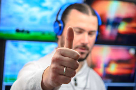 Photo of the video broadcast editor with headphones watching an action on the monitor. Live TV broadcasting processの写真素材