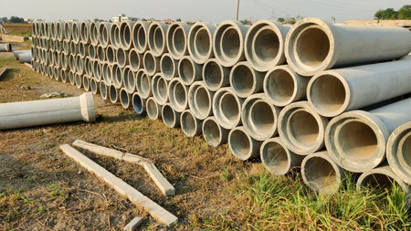Construction site with cement water supply pipes placed neatly in open area showing infrastructure...