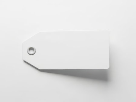 A blank white price tag with a hole at the top left corner, casting a subtle shadow, is placed on a clean white background, providing a minimalist and professional visual representation.の素材