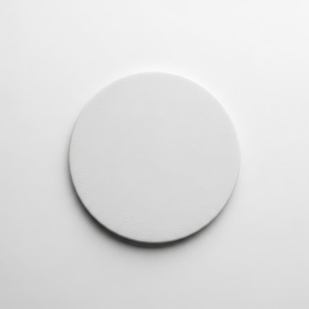 A white round object is placed on a plain white surface. The object is centered in the image and is casting a slight shadow on the surface below it, indicating it is on a white background.の素材