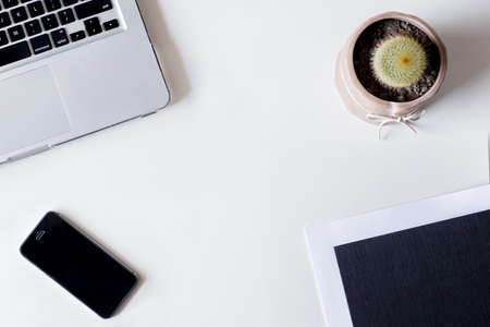 White office desk table with laptop, smartphone, cactus, and glass. Top view with copy space, flat lay.の写真素材