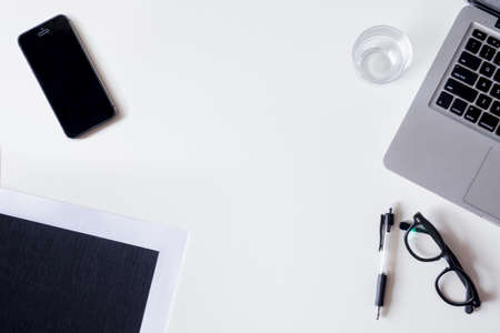 White office desk table with laptop, smartphone, file, and glass. Top view with copy space, flat lay.の写真素材