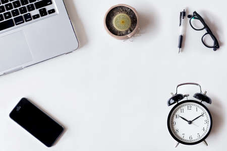 White office desk table with laptop, cactus, smartphone, and glass. Top view with copy space, flat lay.の写真素材
