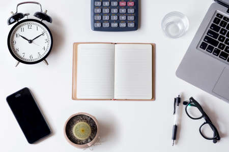 White office desk table with laptop, smartphone, notebook,cactus,calculator and glass. Top view with copy space, flat lay.の写真素材