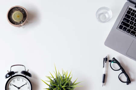 White office desk table with laptop, smartphone, and glass. Top view with copy space, flat lay.の写真素材