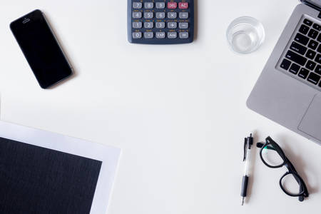 White office desk table with laptop, calculator, smartphone, file, and glass. Top view with copy space, flat lay.の写真素材