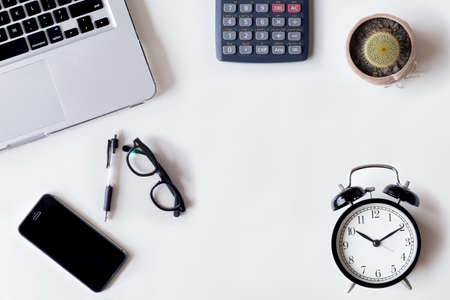 White office desk table with laptop, cactus, smartphone, and glass. Top view with copy space, flat lay.の写真素材