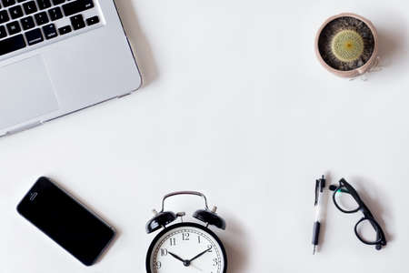 White office desk table with laptop, cactus, smartphone, and glass. Top view with copy space, flat lay.の写真素材