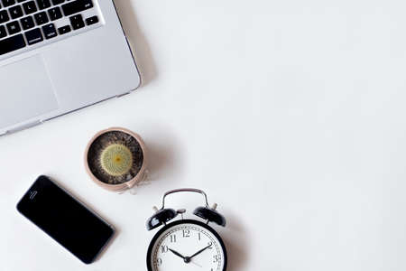 White office desk table with laptop, cactus, smartphone, and glass. Top view with copy space, flat lay.の写真素材