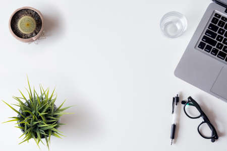 White office desk table with laptop, smartphone, and glass. Top view with copy space, flat lay.の写真素材