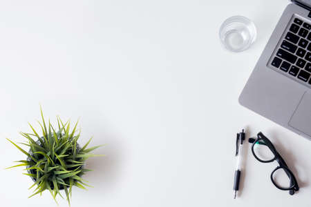 White office desk table with laptop, smartphone, and glass. Top view with copy space, flat lay.の写真素材