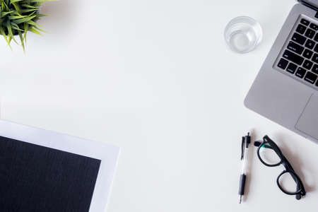 White office desk table with laptop, smartphone, file, plan and glass. Top view with copy space, flat lay.の写真素材
