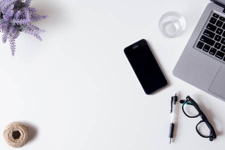 White office desk table with laptop, smartphone, lavender, and glass. Top view with copy space, flat lay.の写真素材