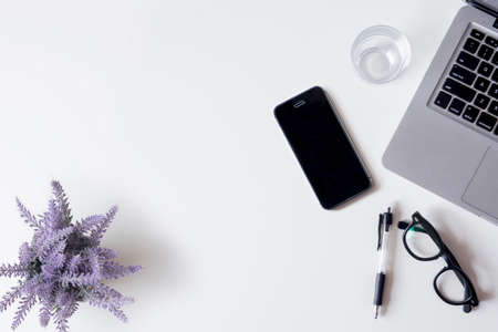 White office desk table with laptop, smartphone, lavender, and glass. Top view with copy space, flat lay.の写真素材