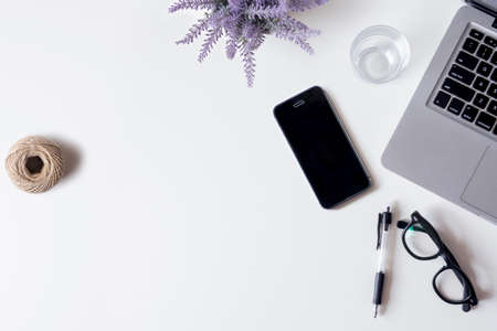 White office desk table with laptop, smartphone, lavender, and glass. Top view with copy space, flat lay.の写真素材