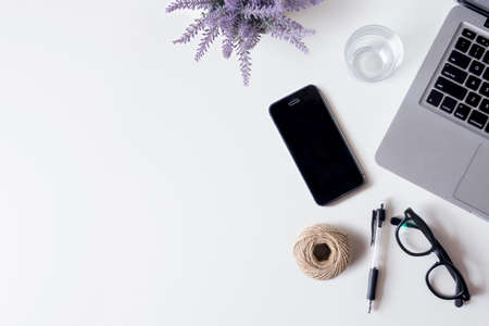 White office desk table with laptop, smartphone, lavender, and glass. Top view with copy space, flat lay.の写真素材