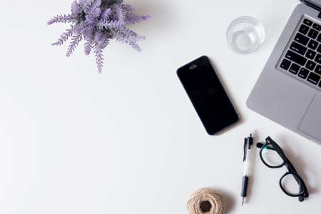 White office desk table with laptop, smartphone, lavender, and glass. Top view with copy space, flat lay.の写真素材