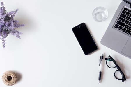 White office desk table with laptop, smartphone, lavender, and glass. Top view with copy space, flat lay.の写真素材