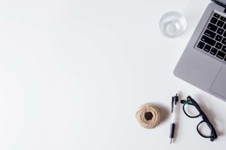 White office desk table with laptop, smartphone, pen,  rope and glass. Top view with copy space, flat lay.の写真素材