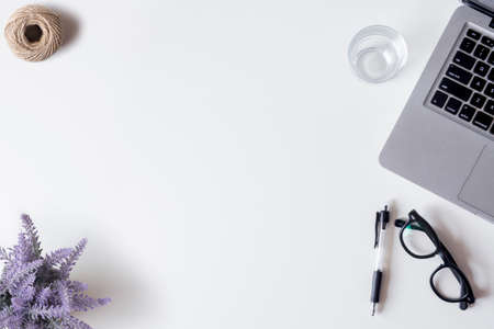 White office desk table with laptop, smartphone, pen, lavender, rope, and glass. Top view with copy space, flat lay.の写真素材