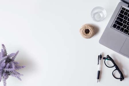 White office desk table with laptop, smartphone, pen, lavender, rope, and glass. Top view with copy space, flat lay.の写真素材