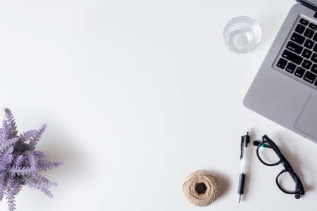 White office desk table with laptop, smartphone, pen, lavender, rope, and glass. Top view with copy space, flat lay.の写真素材