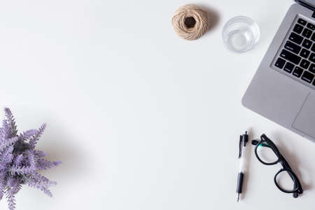 White office desk table with laptop, smartphone, pen, lavender, rope, and glass. Top view with copy space, flat lay.の写真素材