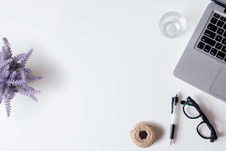 White office desk table with laptop, smartphone, pen, lavender and glass. Top view with copy space, flat lay.の写真素材