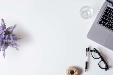 White office desk table with laptop, smartphone, pen, lavender and glass. Top view with copy space, flat lay.の写真素材