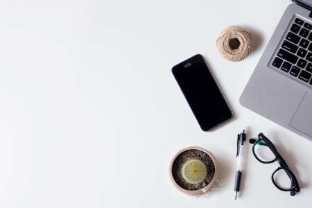 White office desk table with laptop, smartphone, cactus, rope and glass. Top view with copy space, flat lay.の写真素材