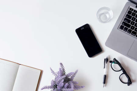 White office desk table with laptop, smartphone, notebook, lavender, and glass. Top view with copy space, flat lay.の写真素材