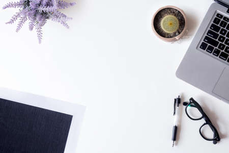 White office desk table with laptop, files, cactus, lavender, and glass. Top view with copy space, flat lay.の写真素材