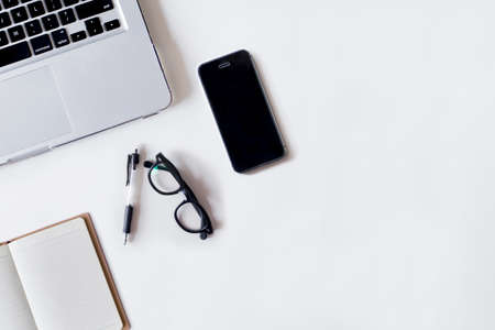 White office desk table with laptop, pen, smartphone, and notebook. Top view with copy space, flat lay.の写真素材