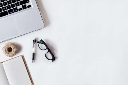 White office desk table with laptop, pen, rope, and notebook. Top view with copy space, flat lay.の写真素材