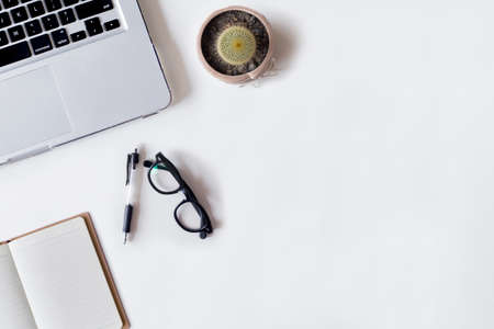 White office desk table with laptop, pen, cactus, and notebook. Top view with copy space, flat lay.の写真素材