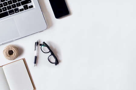 White office desk table with laptop, pen, smartphone, rope, and notebook. Top view with copy space, flat lay.の写真素材