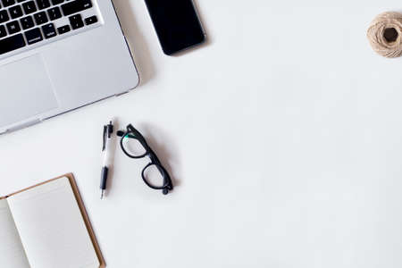 White office desk table with laptop, pen, smartphone, rope, and notebook. Top view with copy space, flat lay.の写真素材