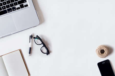 White office desk table with laptop, pen, smartphone, rope, and notebook. Top view with copy space, flat lay.の写真素材