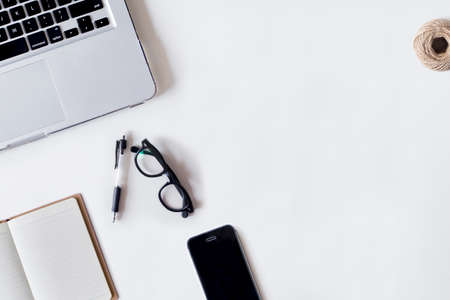 White office desk table with laptop, pen, smartphone, rope, and notebook. Top view with copy space, flat lay.の写真素材