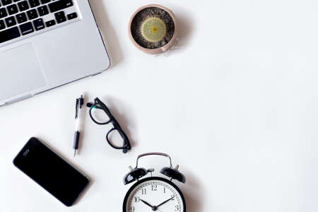White office desk table with laptop, smartphone, alarm,cactus and glass. Top view with copy space, flat lay.の写真素材