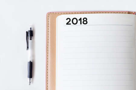 Conceptual,notebook on a white table. open diary and pen with 2018 wordsの写真素材