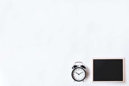 White office desk table with chalkboards and alarm clock. Top view with copy space, flat lay.の写真素材