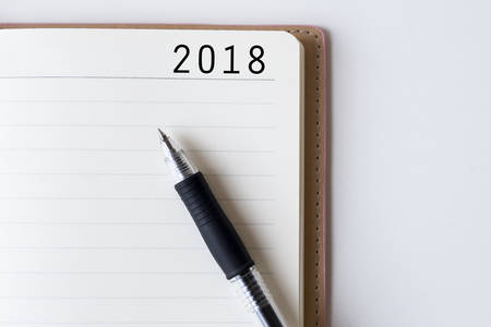 Conceptual,notebook on a white table. open diary and pen with 2018 wordsの写真素材