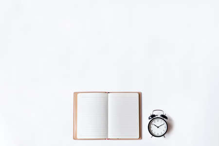 White office desk table with open diary and alarm clock, Top view with copy space, flat lay.の写真素材