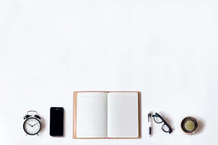 White office desk table with open diary, pen, alarm clock, cactus and smartphone, Top view with copy space, flat lay.の写真素材